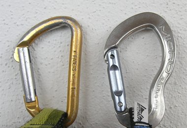 Links (in Gold) ein im Umfang schon deutlich dünnerer Karabiner, rechts ein neuer (blank).